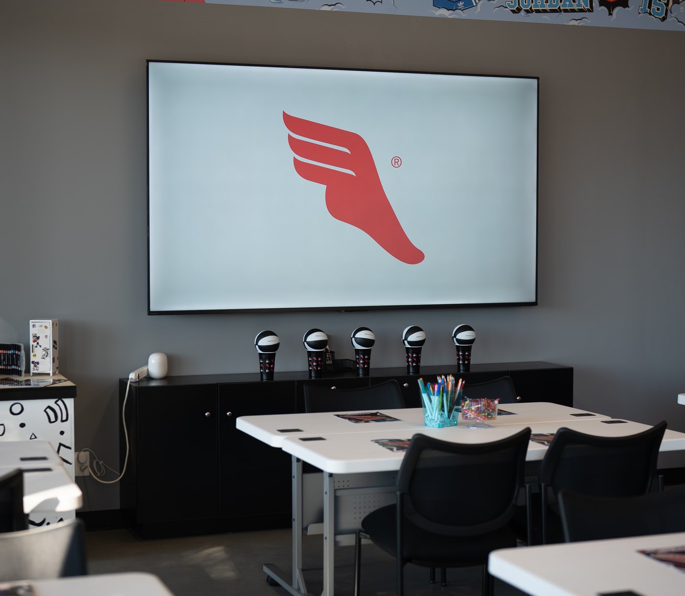 The community room at The Athlete's Foot Raleigh, set with tables, chairs and a presentation screen